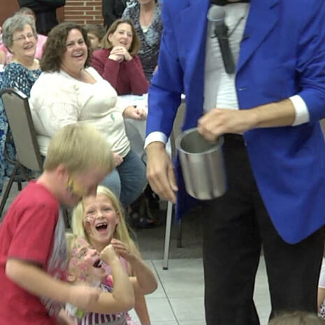 Fabjance the magician pulls coins from children's ears during a Chicago area magic performance!